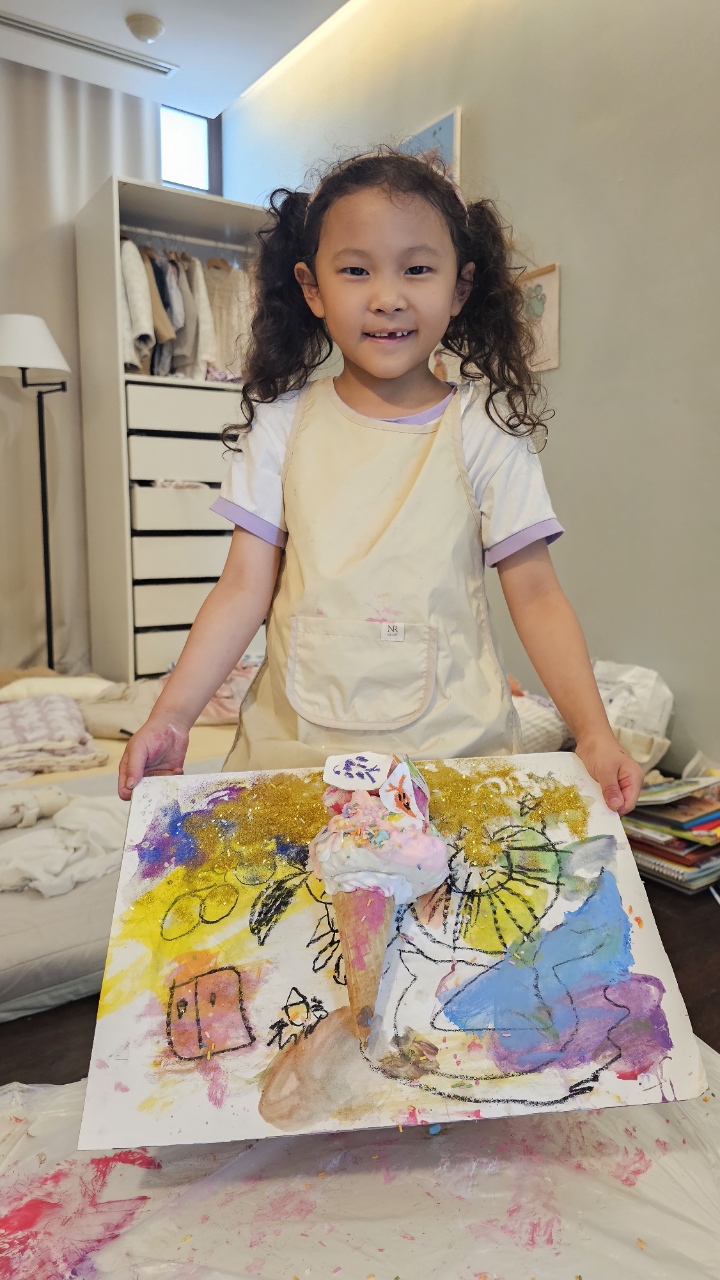 Proudly presenting her colorful mixed-media artwork with glitter and 3D elements